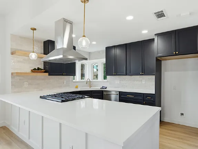 Dramatic kitchen remodel with matte black upper cabinets, white quartz island, stainless range hood and marble tile backsplash in Dallas