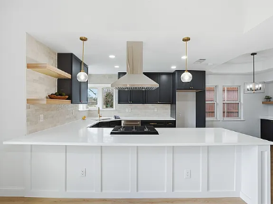 Two-tone kitchen renovation featuring black upper cabinets, white shaker island, pendant lighting and stainless appliances in DFW