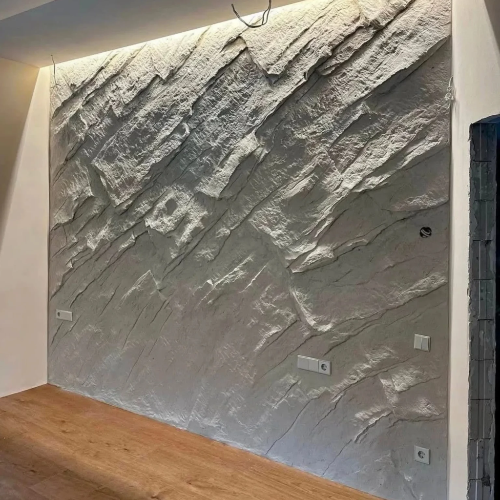 Interior wall with relief pattern resembling stacked stone or rock with integrated linear lighting by 448 Developments DFW