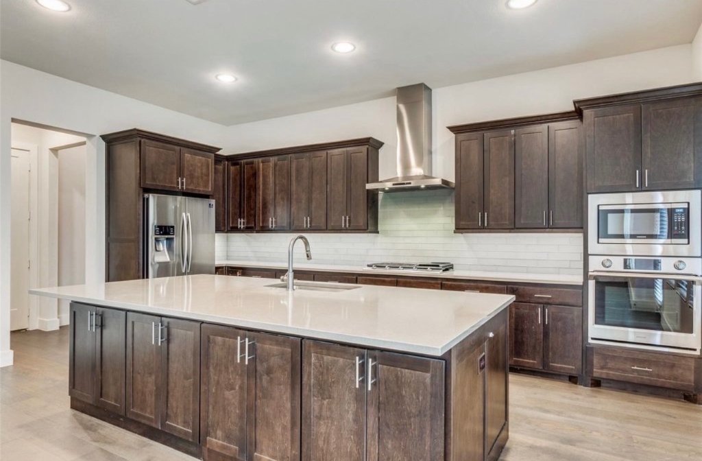 Kitchen renovation with dark espresso shaker cabinets, large white quartz island, stainless steel appliances and subway tile backsplash in DFW
