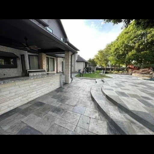 A large, multi-level stamped concrete patio with geometric patterns and integrated steps, perfect for a modern backyard renovation in Dallas.