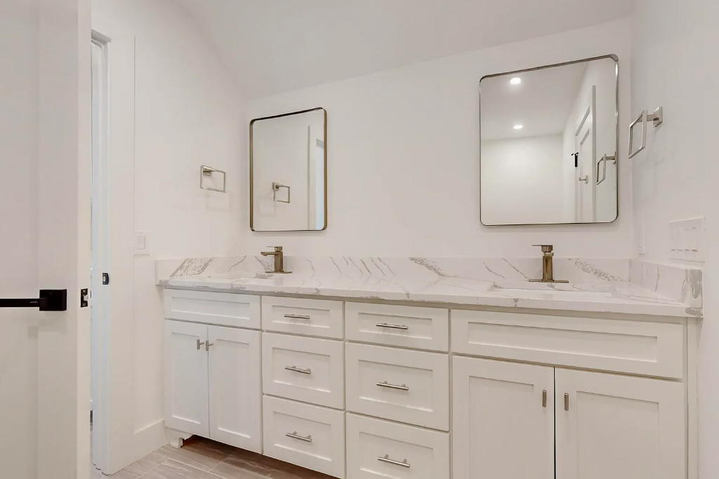 Elegant bathroom remodel with full marble tile shower, gold framed glass door, vessel sink, grey vanity and gold fixtures in Dallas Texas