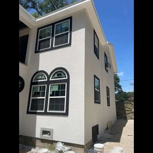 A newly finished home exterior with clean white stucco walls, contrasting black-trimmed windows including an arched design, reflecting a comprehensive DFW home makeover.