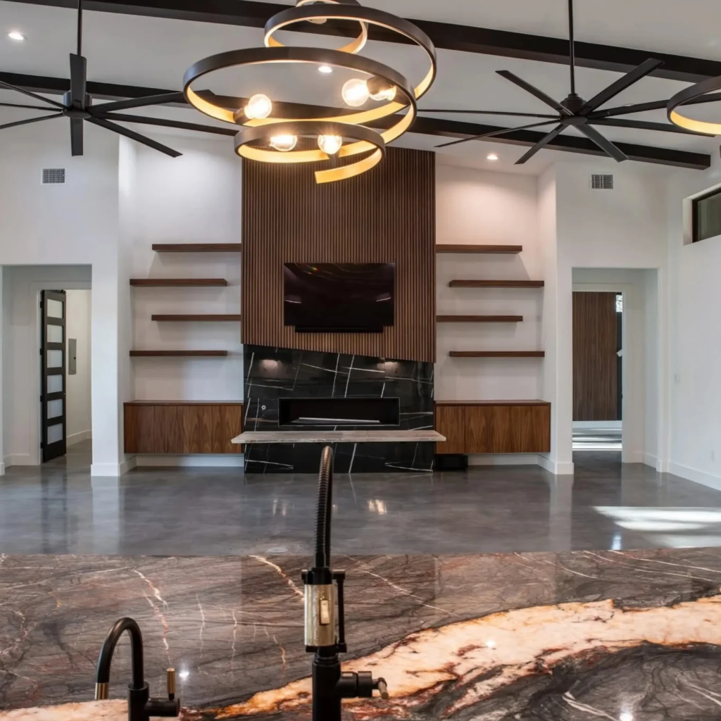 Spacious open concept living room with wooden slat accent wall, large circular modern chandelier, and dark ceiling beams by 448 Developments Dallas TX