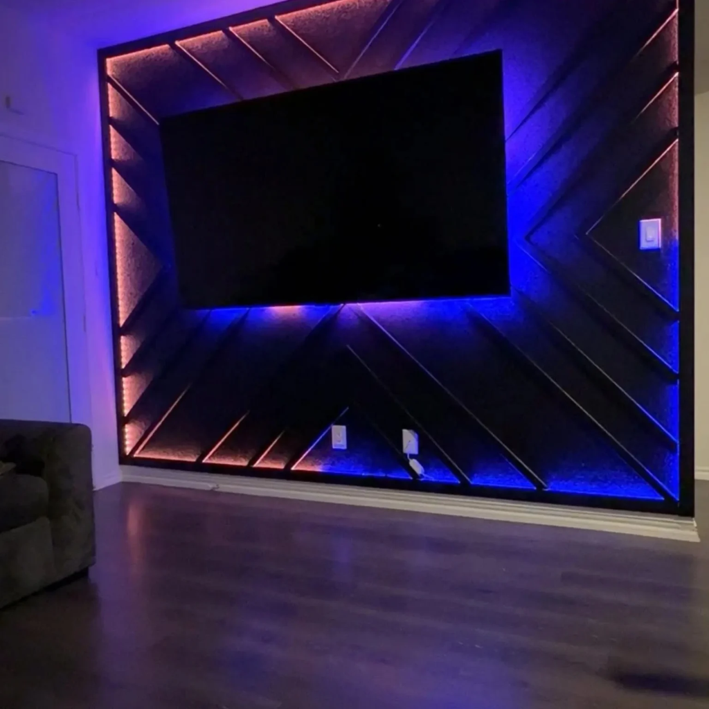Contemporary media wall with geometric panels and red and blue LED backlighting surrounding mounted television by 448 Developments DFW