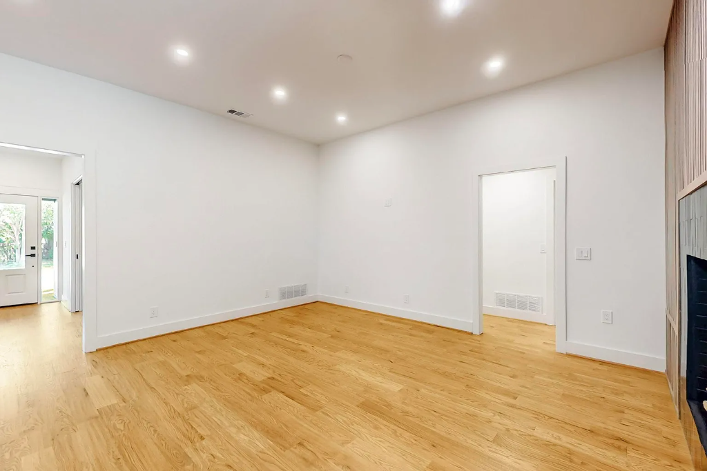 Continuous light oak hardwood flooring extending through multiple rooms in a modern home remodel with recessed lighting and clean white walls by 448 Developments Fort Worth TX