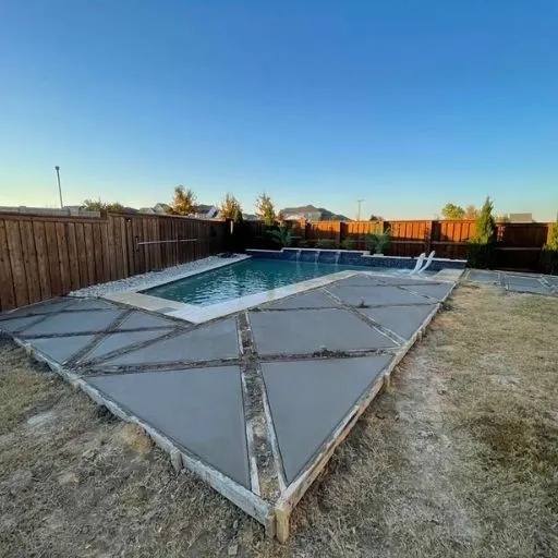 Unique geometric patterned stamped concrete pool deck installation, providing a stylish and durable surface for a backyard swimming pool in the Dallas area. Specializing in custom concrete work.