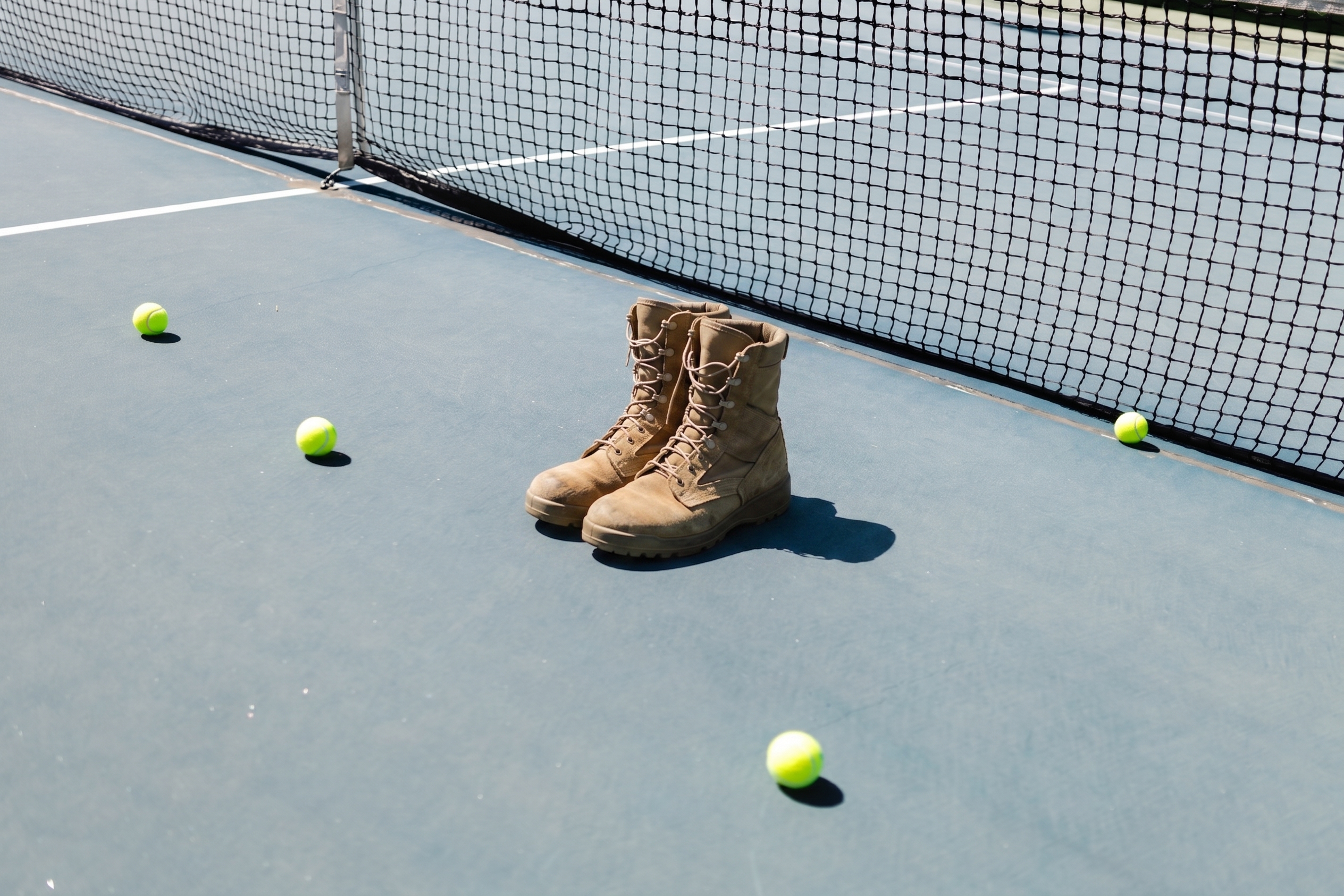 Combat boots and tennis balls on a tennis court