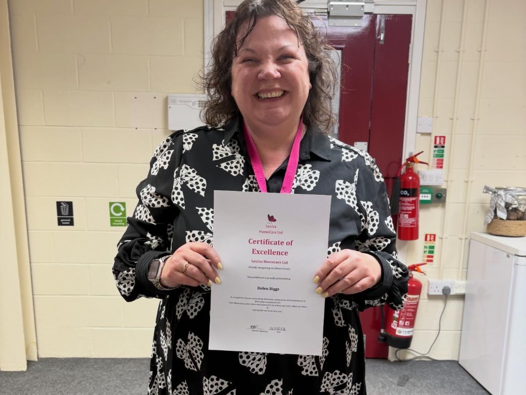 Helen Biggs holding certificate of excellence