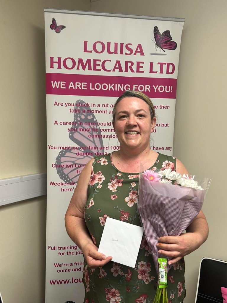 Staff member with flowers in front of Louisa Homecare banner
