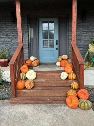 Wooden porch staircase with abundant pumpkin display and burgundy mums — real installation