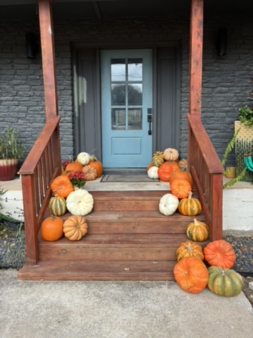 Front porch entrance with mixed pumpkins gourds and mums on wooden steps — real installation