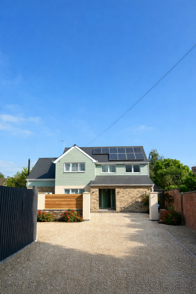 House with green cladding and gravel driveway