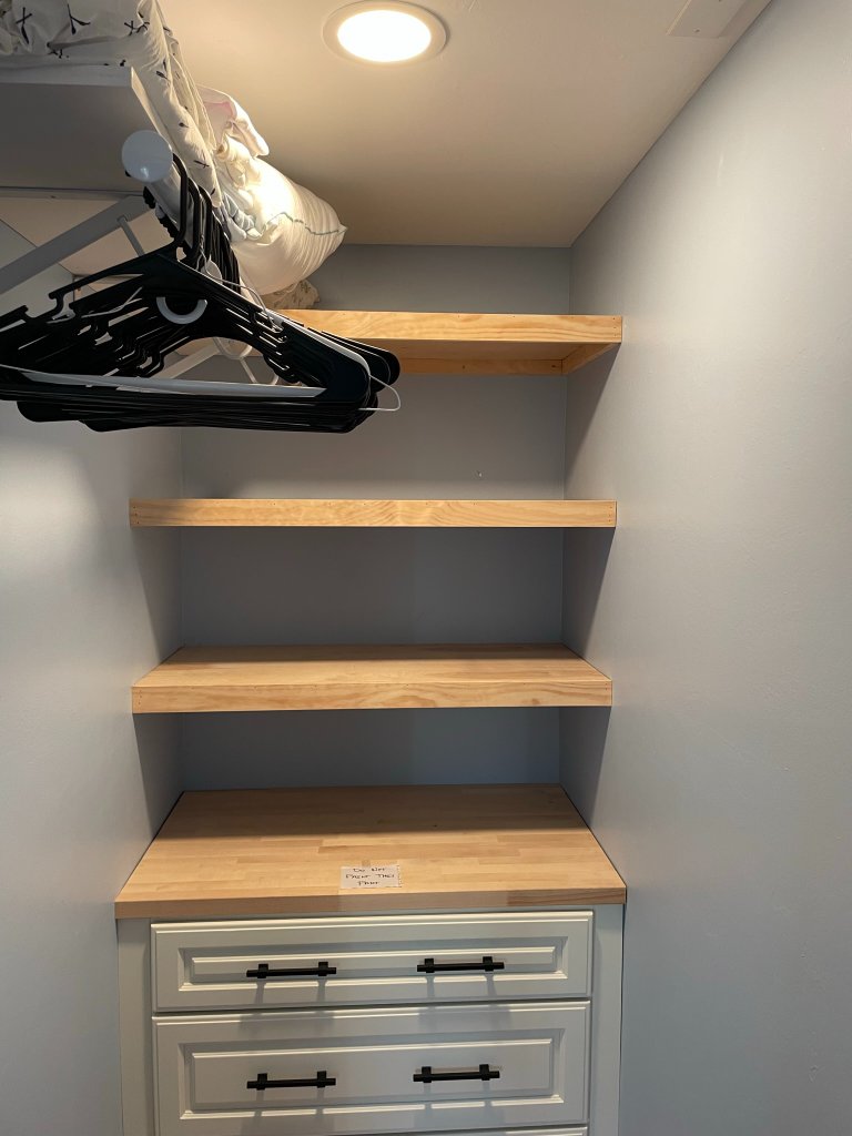 Custom built-in closet with natural wood shelves and white cabinetry