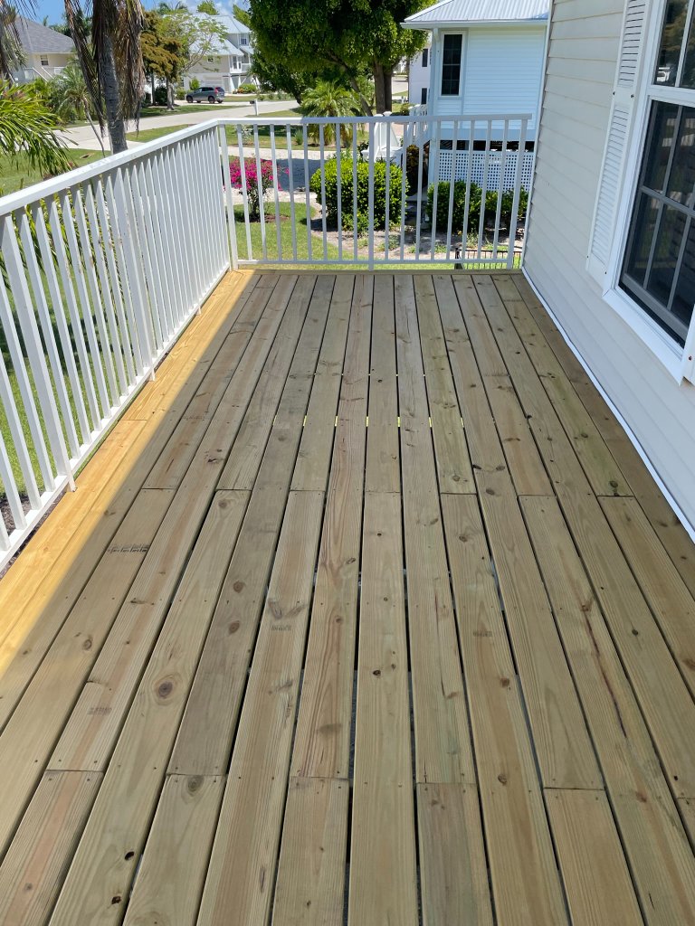 Finished wooden deck with white railing and natural wood planks