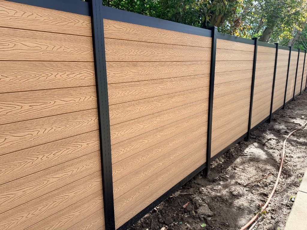 Trex composite fence with warm wood-grain boards and black aluminum posts