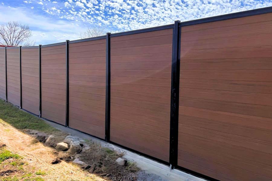 Composite privacy fence with horizontal cedar-tone boards and black steel framing