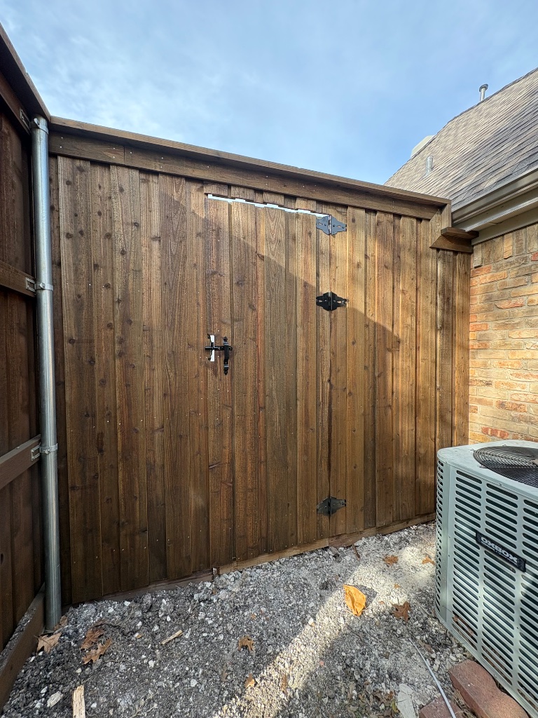 Cedar fence gate with dark stain, black hardware hinges and latch detail