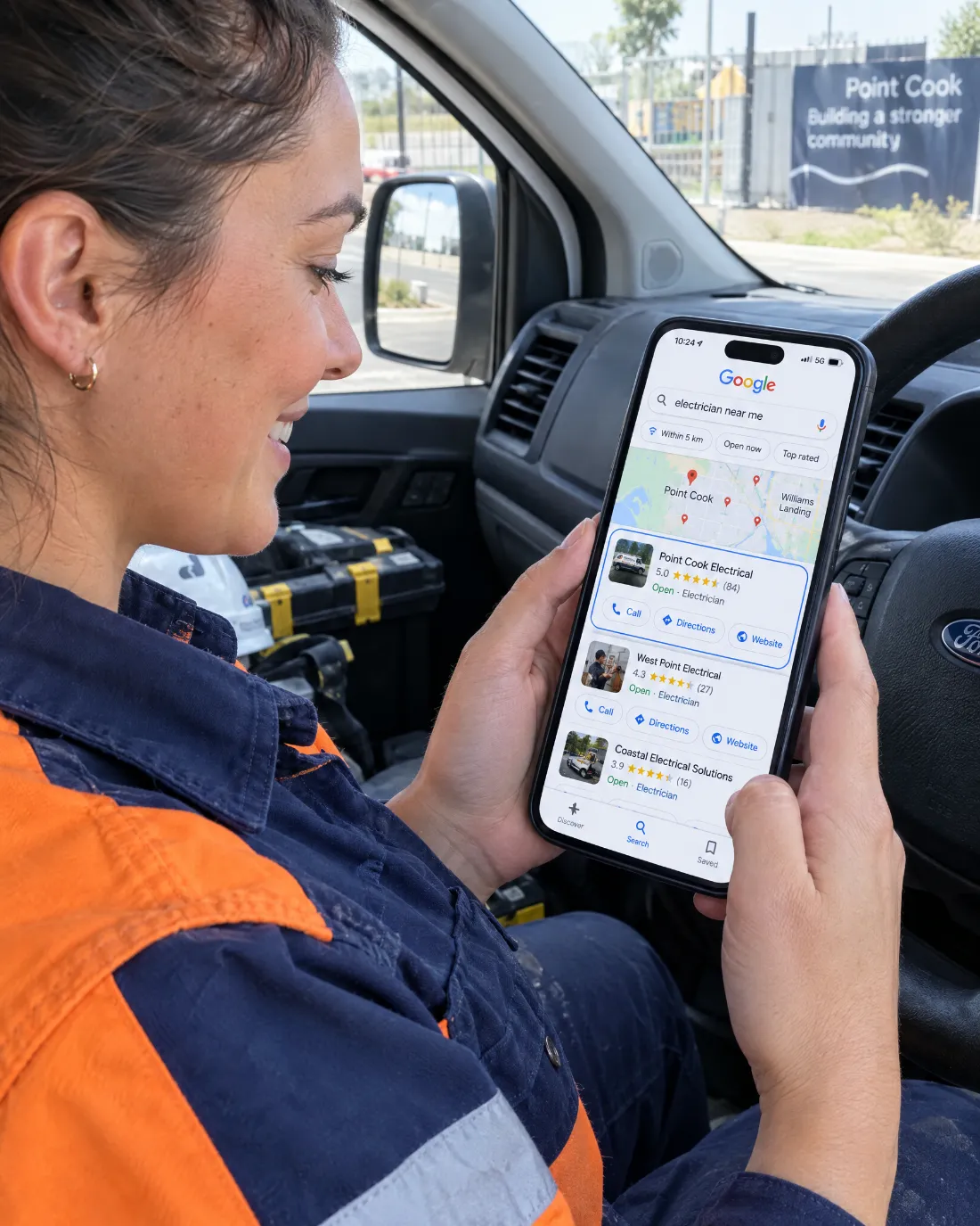 Electrician checking Google Maps results on phone in her van
