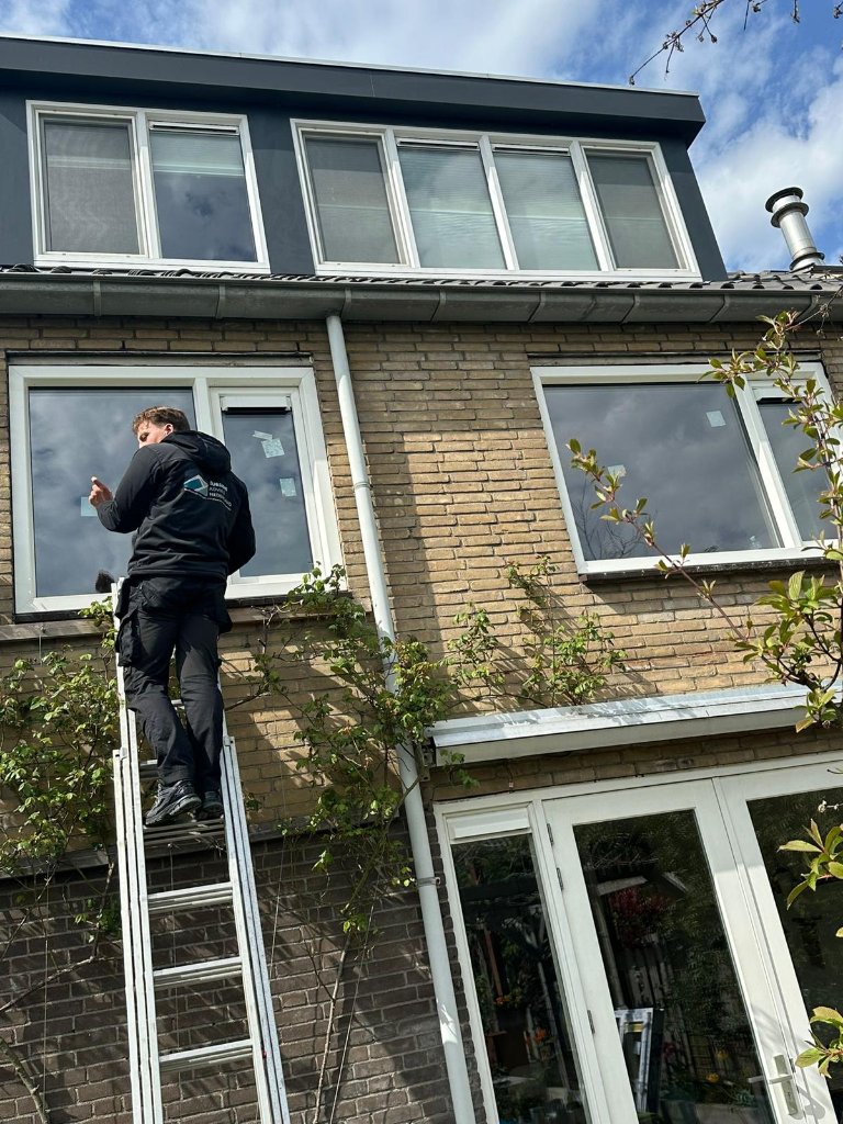 Medewerker op ladder aan de gevel van een woning