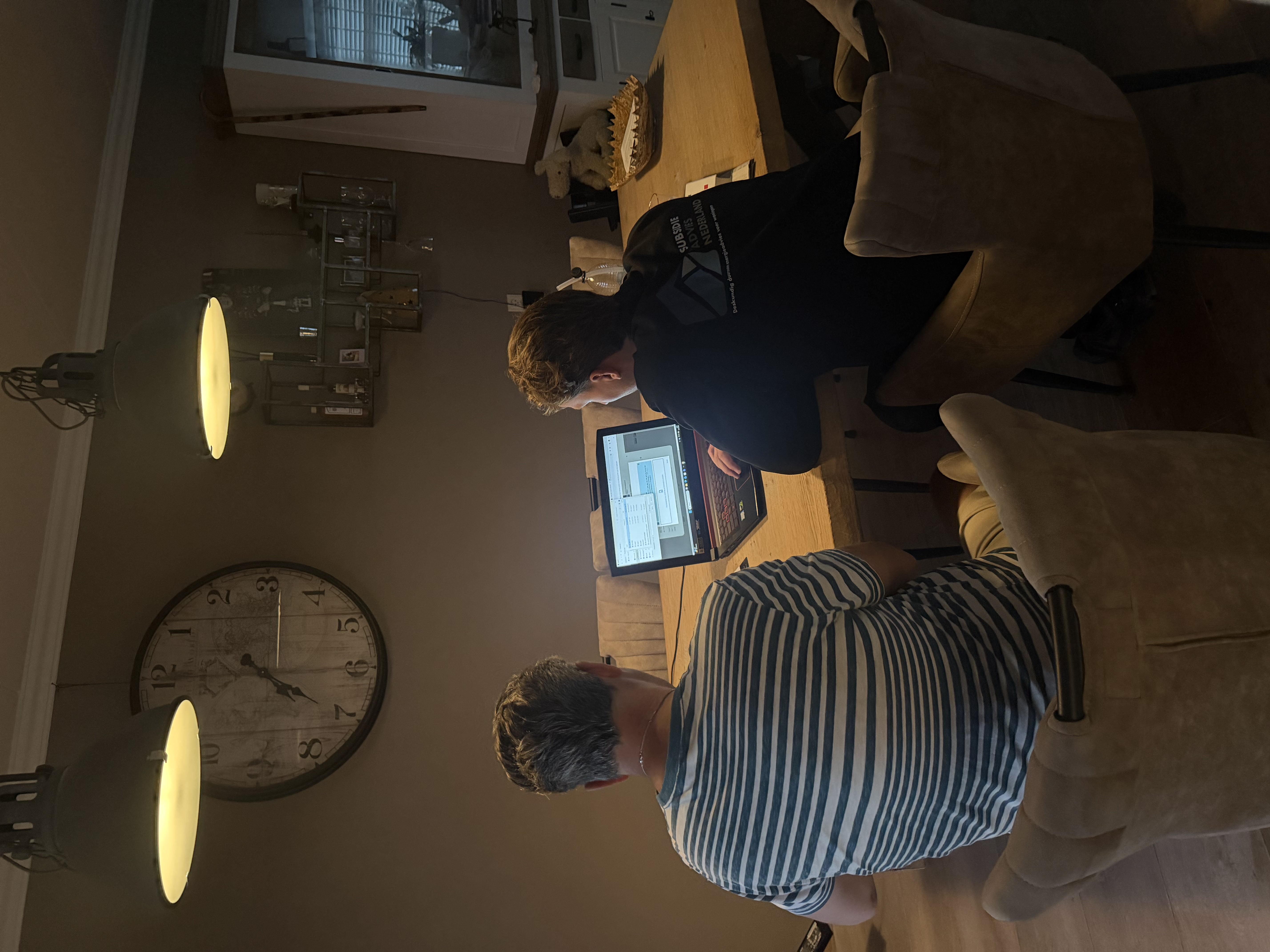 Twee medewerkers werken samen achter een laptop aan de eettafel