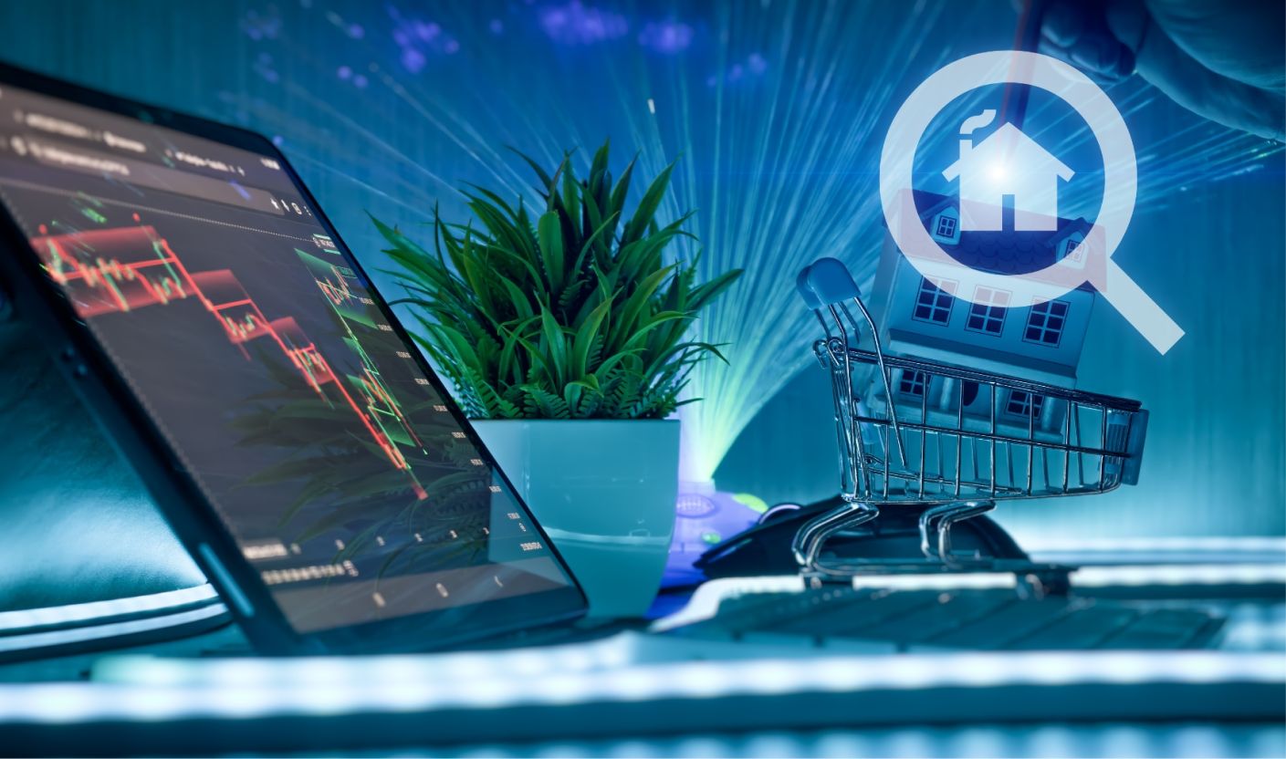Model domu w koszyku obok wykresów finansowych na ekranie tabletu