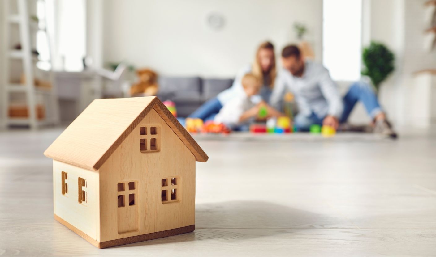 Wooden model house with a family together in the background