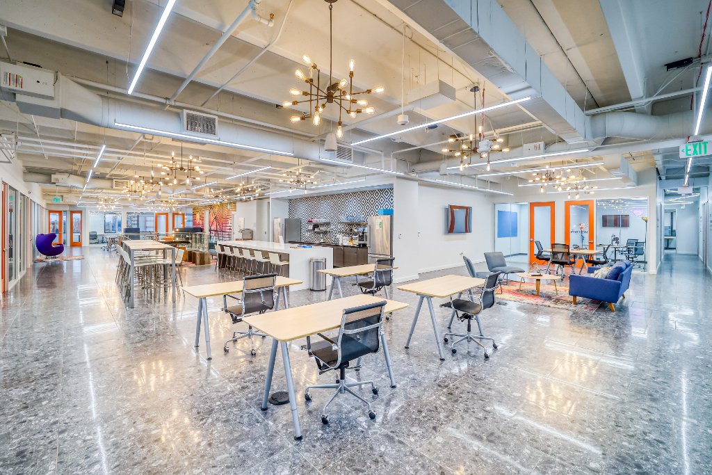 Suites — Open Co-Working Floor with Kitchen & Chandelier Lighting