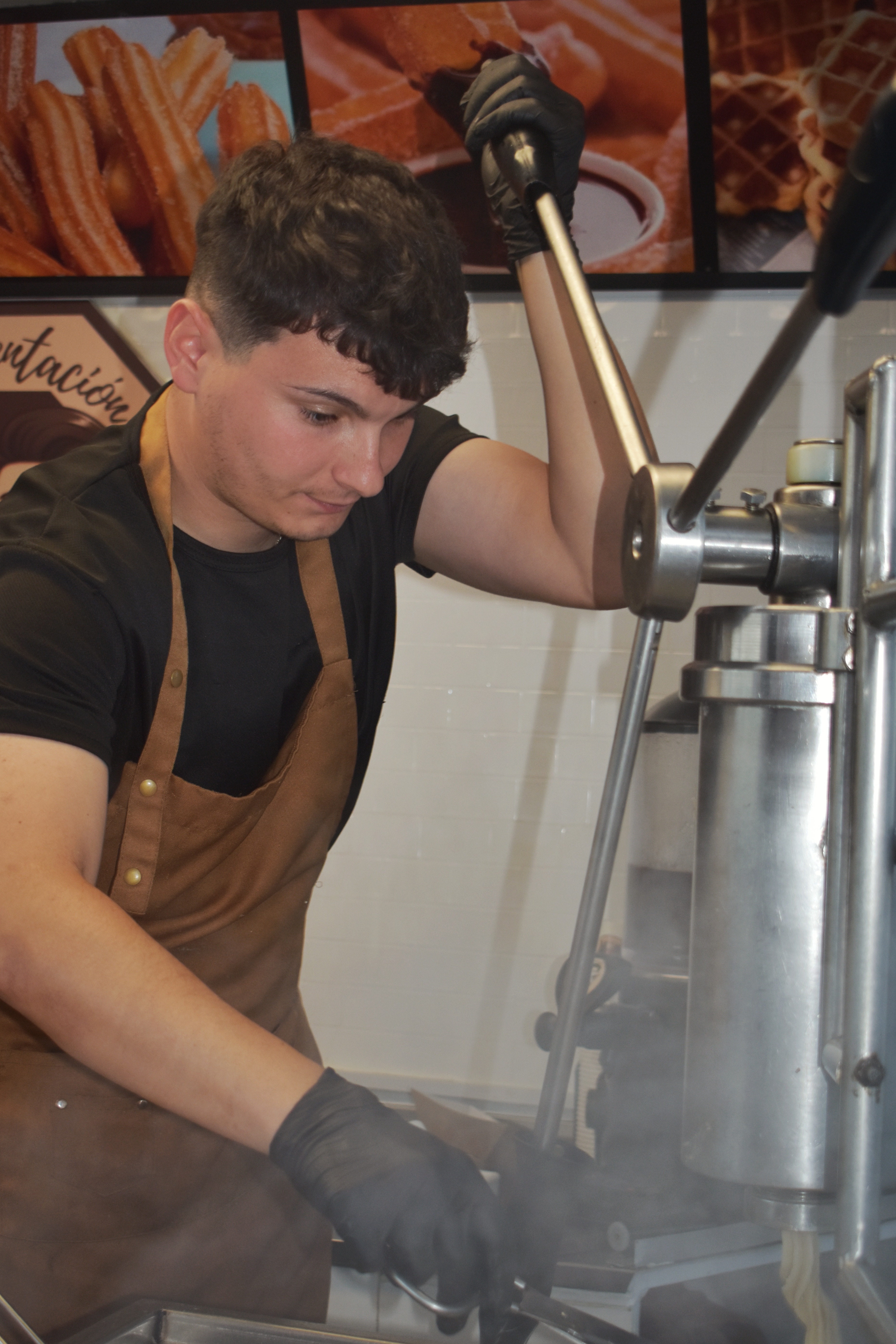 Miembro del equipo elaborando churros con la máquina en la churrería