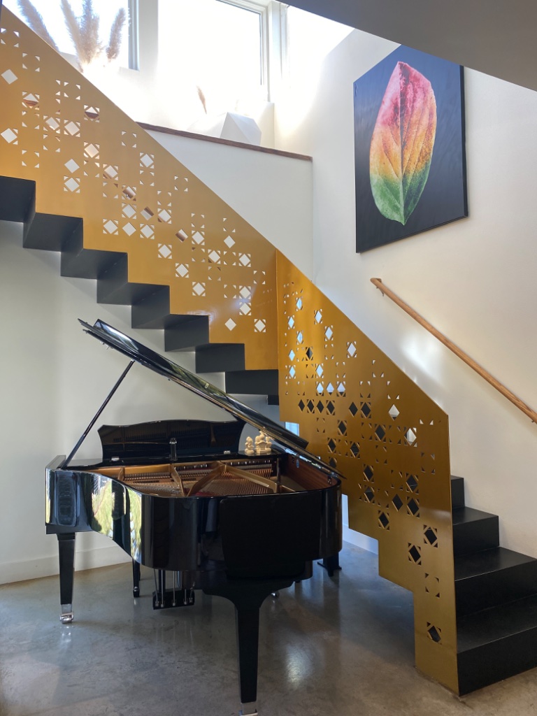 Gold staircase with grand piano and colorful leaf artwork