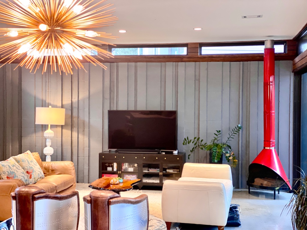Living room with large leather sofa, red fireplace, and sputnik chandelier