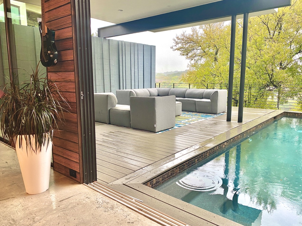 Pool view from interior with guitar on wood-paneled wall