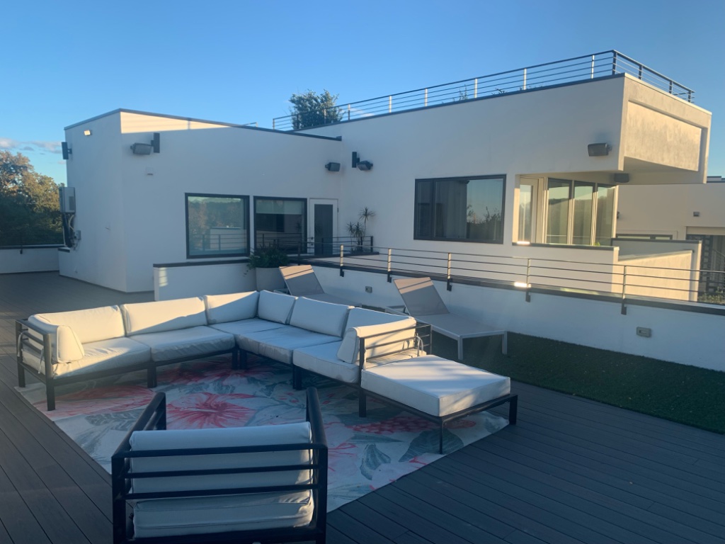 Rooftop deck with white sectional and sun loungers