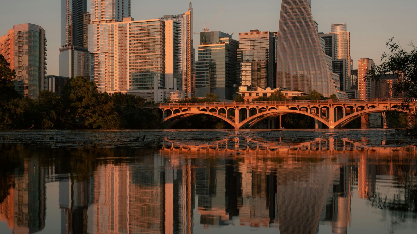 Downtown Austin and the Lamar Boulevard Bridge reflected in Lady Bird Lake at sunset. Photo by Alberto Alvarez, sourced through Canva.
