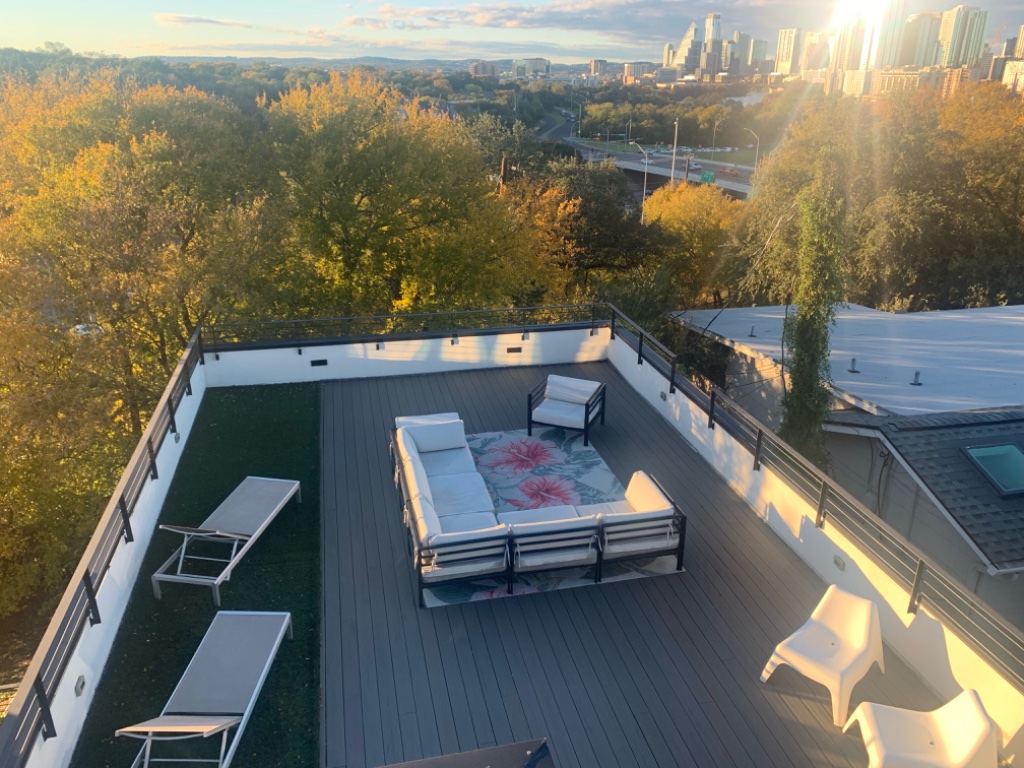 Rooftop deck with white sectional and Austin skyline at golden hour