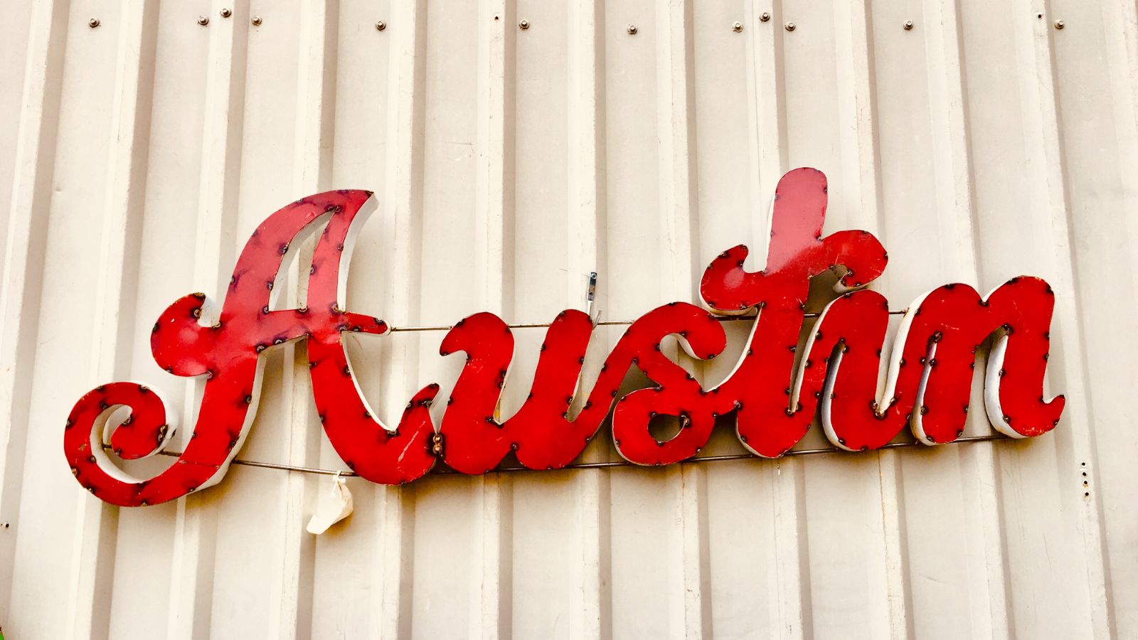 Red Austin lettering on a white wall. Real photograph by RoschetzkyIstockPhoto / Getty Images, sourced through Canva.