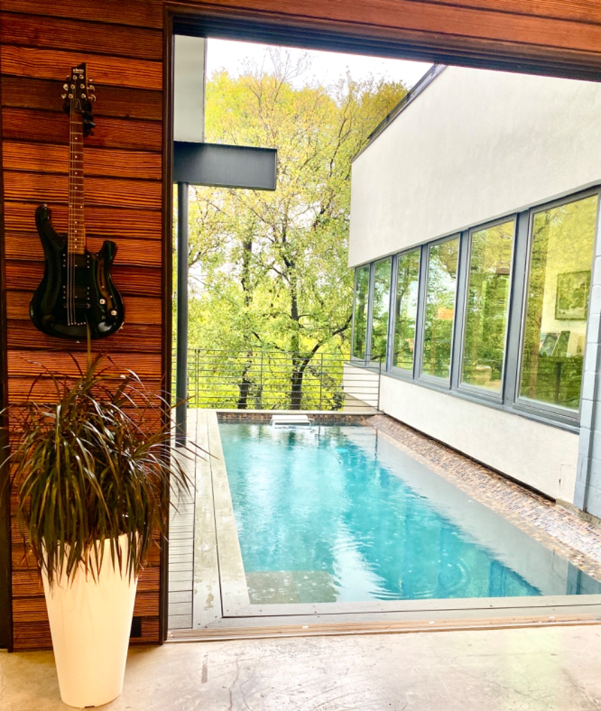 Pool with guitar wall art and lush green trees
