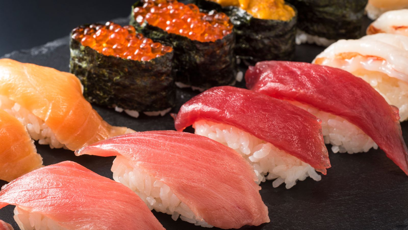 Assorted nigiri sushi on a dark platter. Illustrative stock photograph by kuppa_rock / Getty Images, sourced through Canva; not photographed at Uchi.