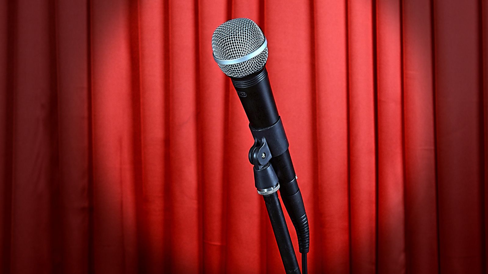 Microphone on Stand on Red Curtain Background. Real photograph by pixelshot, sourced through Canva. Illustrative stock photo; not a photograph of the venues or services reviewed.