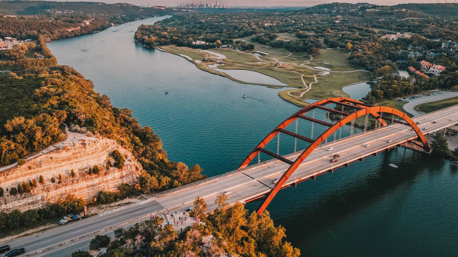 Aerial view of Pennybacker Bridge crossing Lake Austin, with wooded hills and the river. Photo by Raymond Palmer / Getty Images, licensed through Canva.