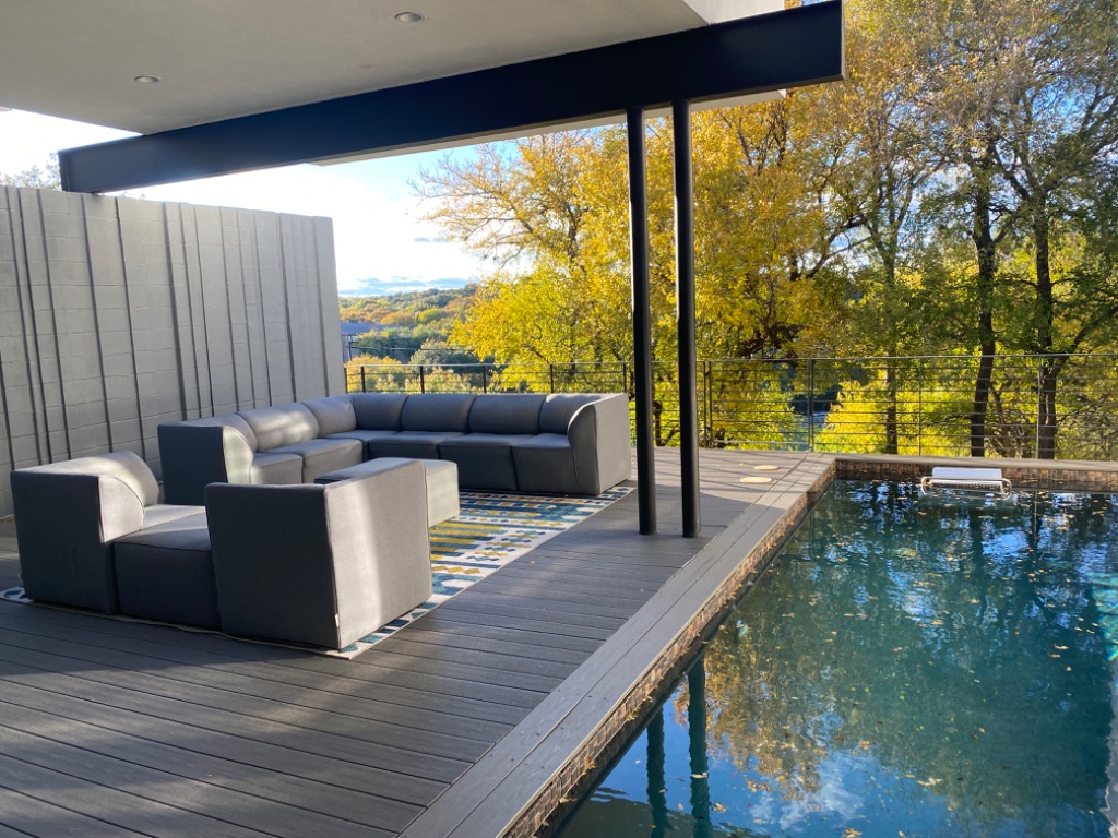 Pool deck with grey sectional sofa and autumn treetop views