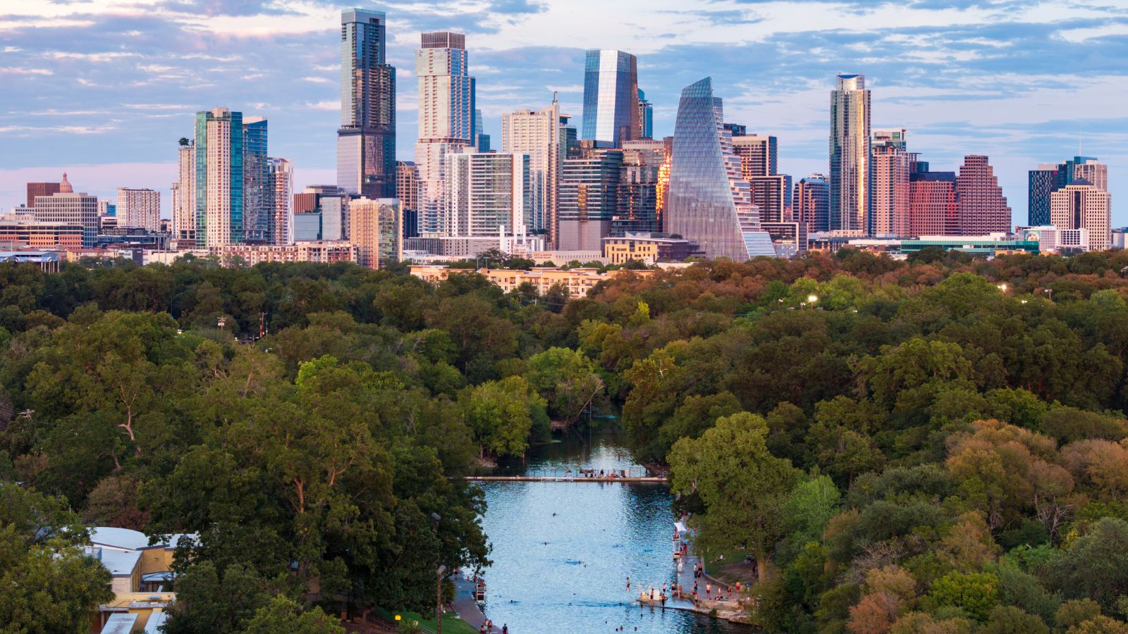 Aerial View of the Austin Skyline at Sunset over Barton Springs.. Real photograph by Backyard Productions, sourced through Canva.
