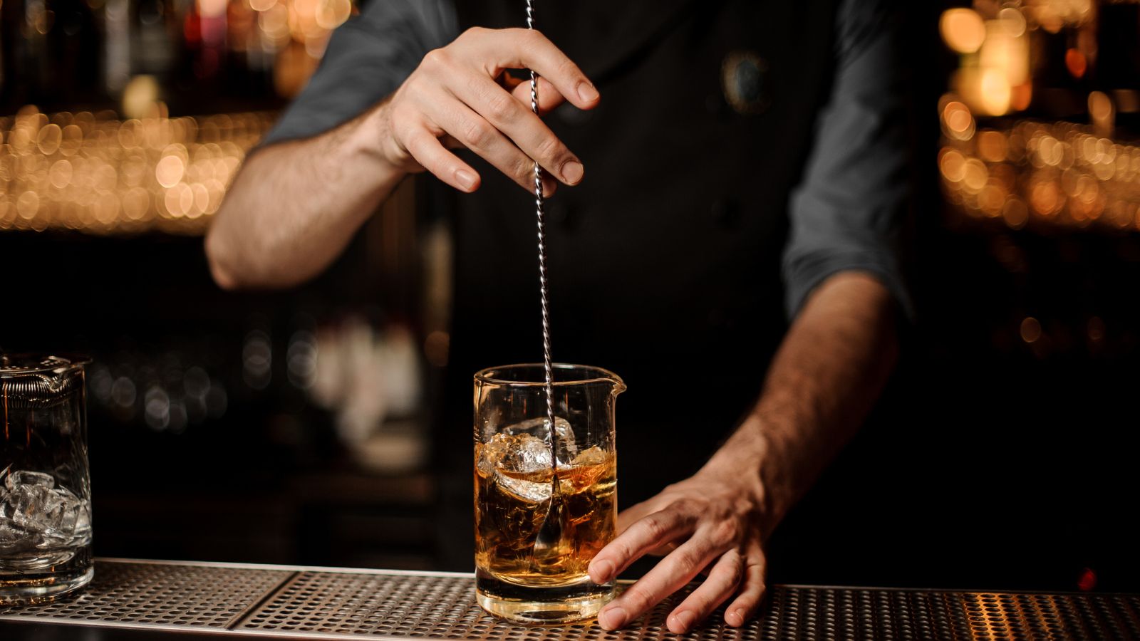 Male bartender stirs alcohol cocktail with bar spoon. Real photograph by MaximFesenko / Getty Images, sourced through Canva. Illustrative stock photo; not a photograph of the venues or services reviewed.