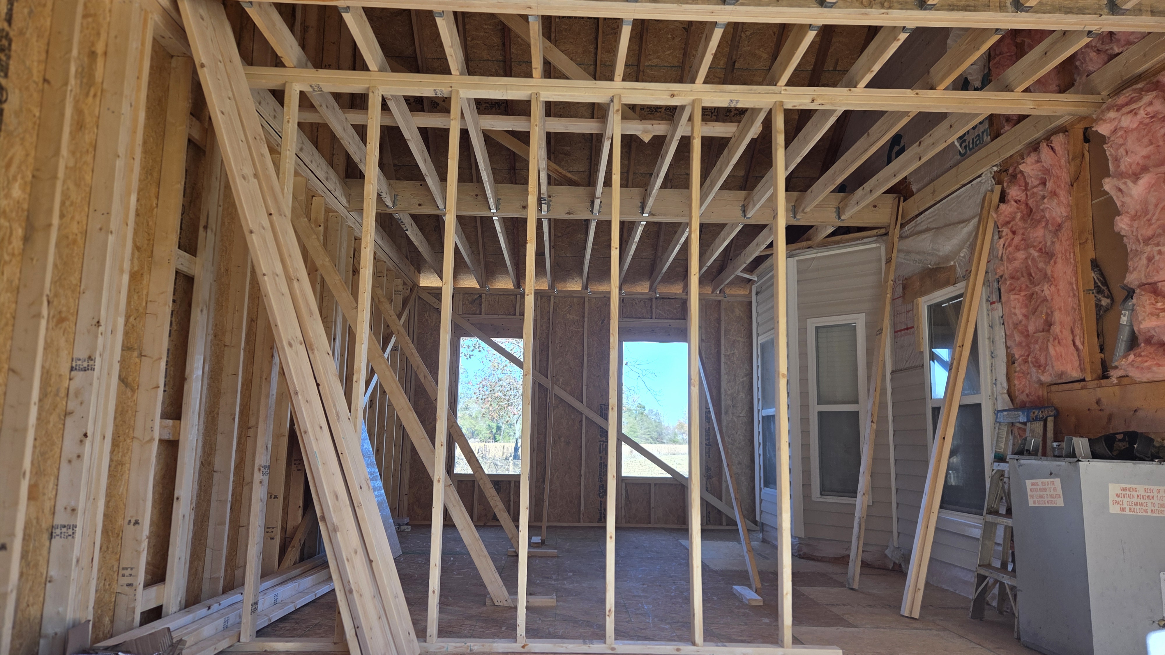 Interior of the Clayton addition showing braced wall framing, rafters, and new window openings