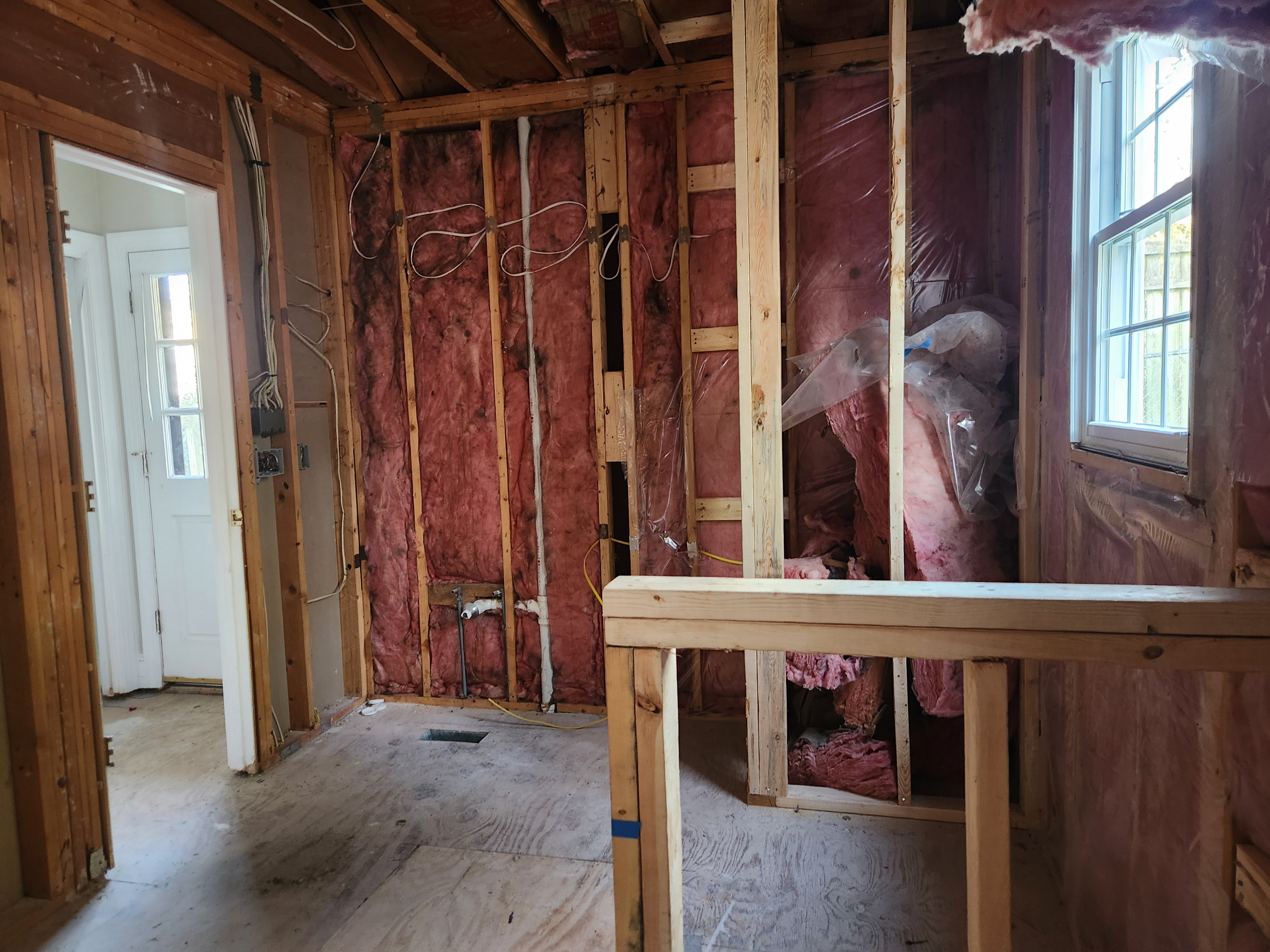 Opened wall bays showing rough electrical wiring and new plumbing lines during the Raleigh remodel