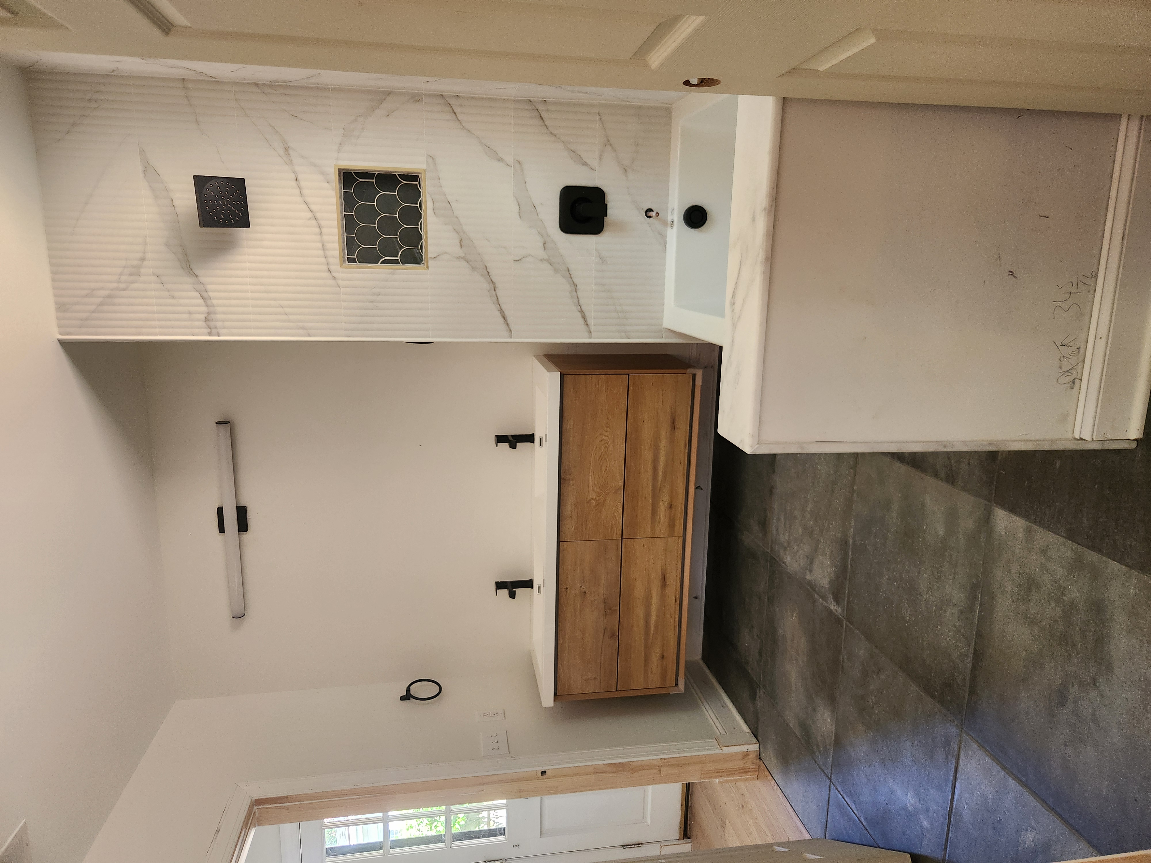 Finished bathroom with floating double vanity, marble-look shower surround, tile niche, and soaking tub