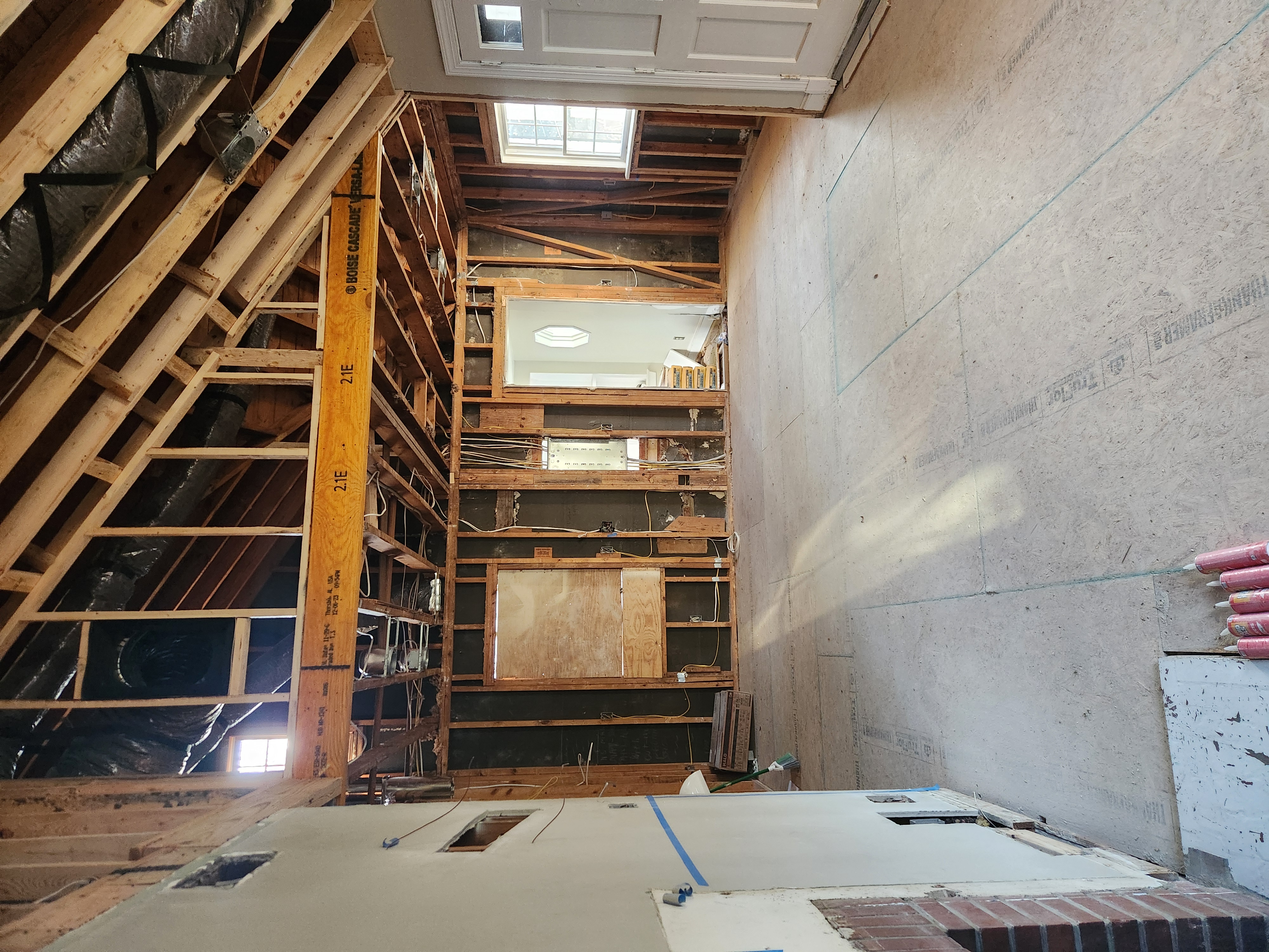 New engineered ridge beam and open rafters framing the vaulted living room ceiling during the Raleigh remodel