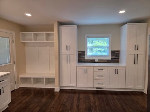 Mudroom bench with cubbies and floor-to-ceiling white pantry cabinets in the remodeled rental
