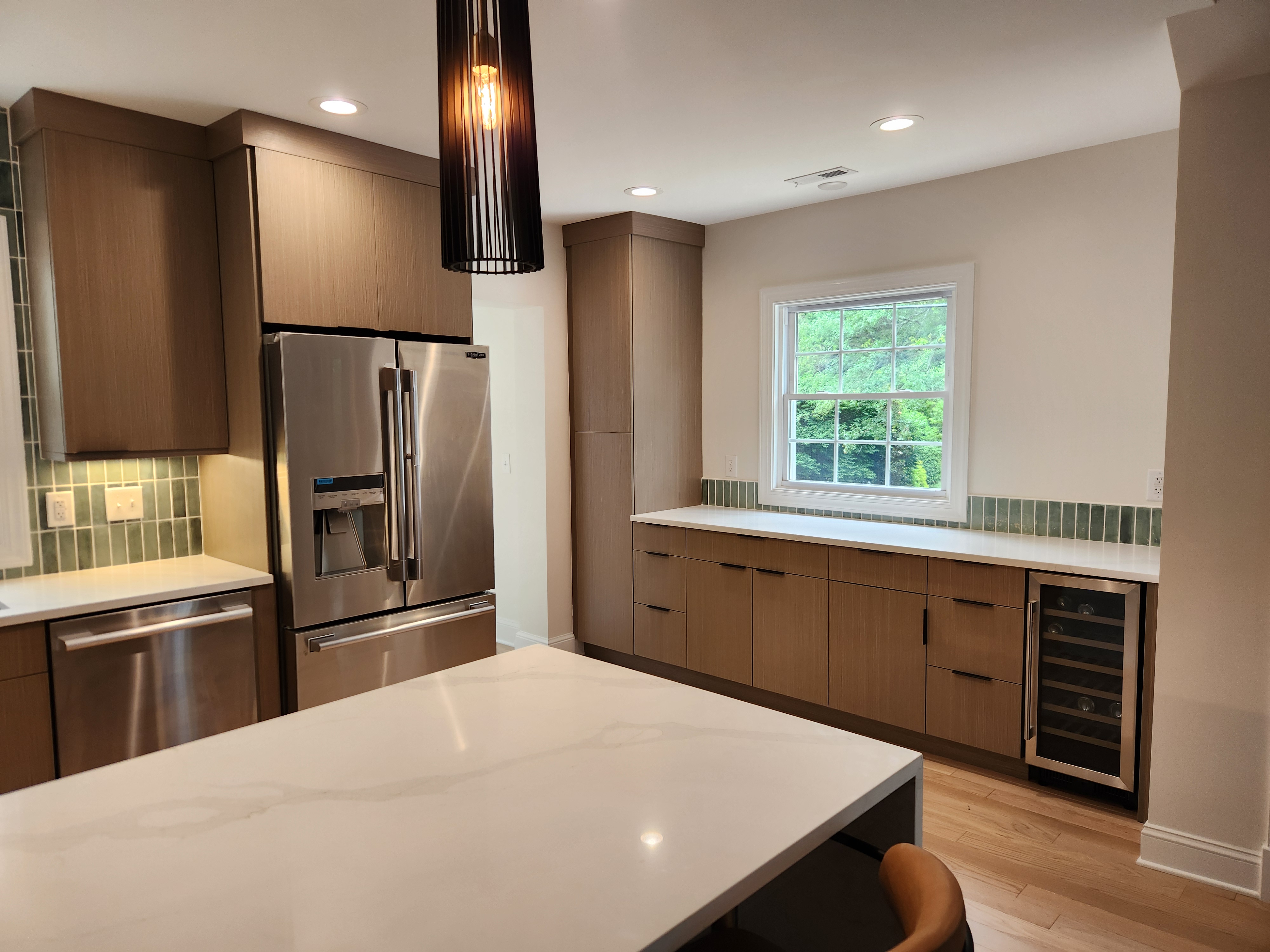 Finished kitchen beverage run with quartz counter, wine fridge, and full-height pantry cabinets