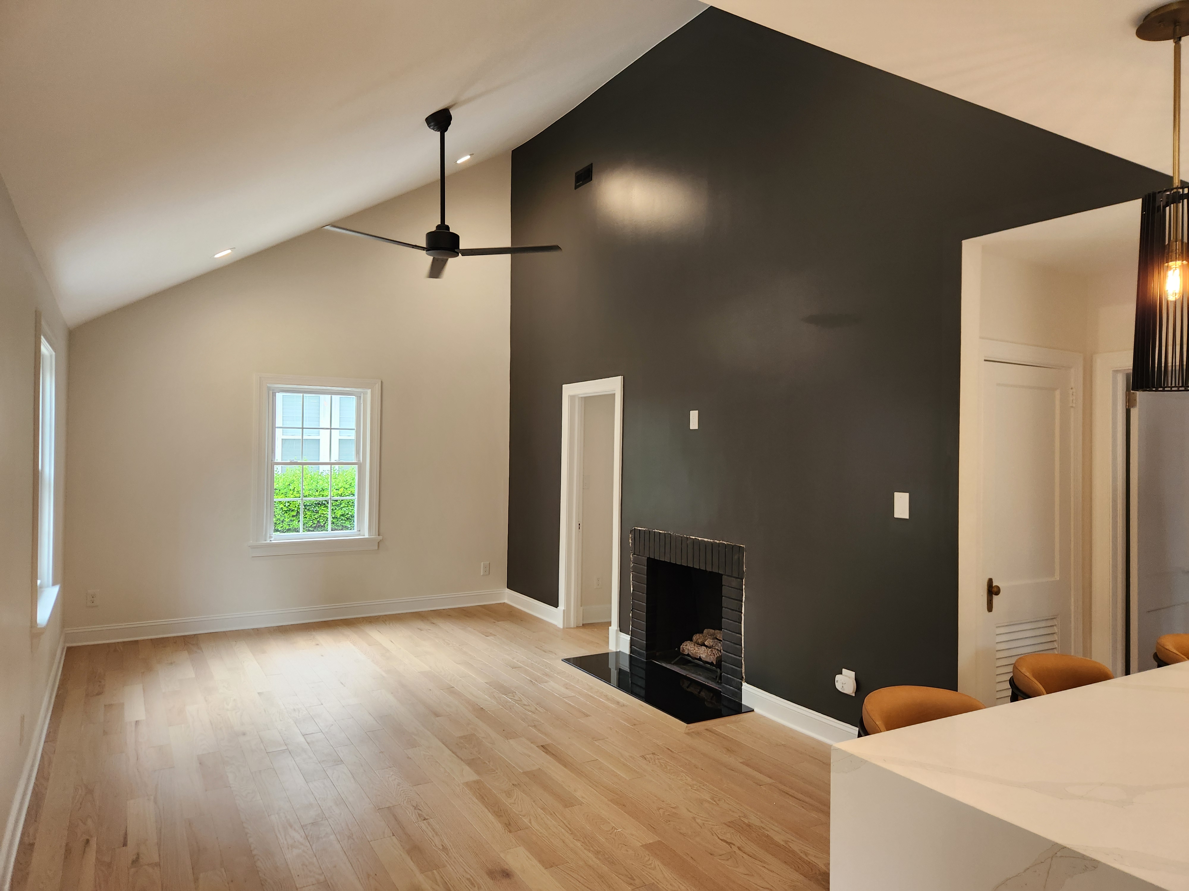 Finished vaulted living room with dark fireplace accent wall and white oak floors in a downtown Raleigh remodel